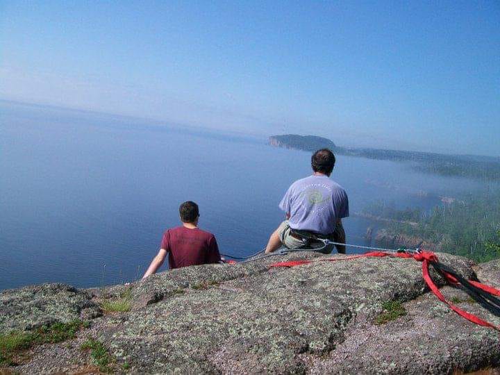 Brad Nagel and another person look out over a body of water after a climb.